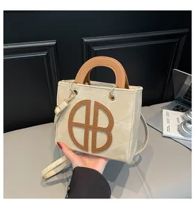 Sac chic en toile beige avec anses en cuir marron et détail ajouré 'AB' élégant