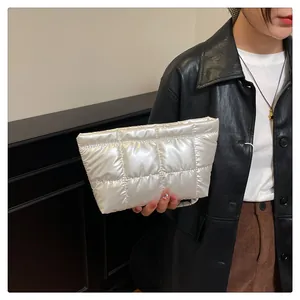 Gros plan détaillé d'une pochette matelassée argentée tenue par un mannequin en veste de cuir