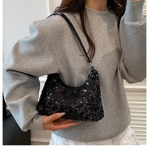 Close-up of black sequined crescent bag with silver rings and leather shoulder strap