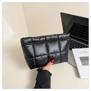 Vue détaillée de la texture matelassée noire et du fini en nylon brillant du sac à main