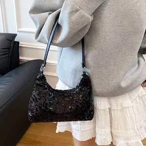 Chic black sequin crescent shoulder bag worn by model in a minimalist indoor setting