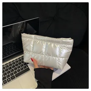 Détail de la pochette matelassée argentée avec coutures carrées et zip doré