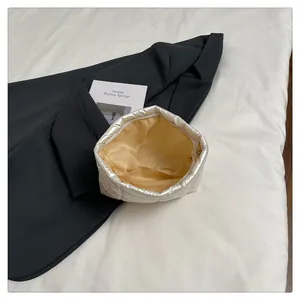 Détail d'une trousse de maquillage argentée matelassée avec fermeture éclair et doublure
