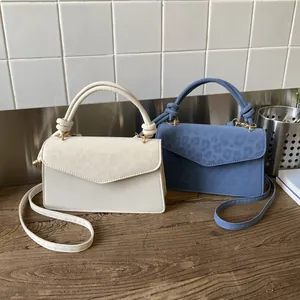 Detail of beige and blue leopard print handbags with knotted handles on a wooden table
