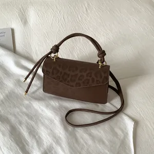 Close-up of leopard print flap detail and knotted handle on a brown leather bag