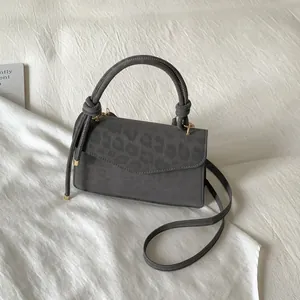 Close-up of charcoal leopard print handbag with knot detail and golden hardware