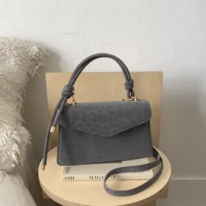 Detail of grey leopard pattern suede handbag with unique knot handle and gold hardware