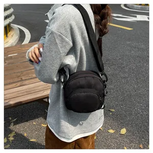 Outdoor lifestyle shot of a black nylon crossbody bag with multi-zipper pockets