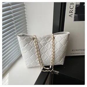 Detail shot of white quilted leather tote bag with classic diamond stitching and gold chain