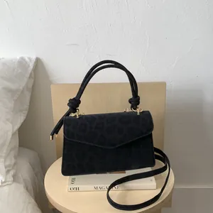 Close-up of black leopard print crossbody bag with knotted handle and gold hardware