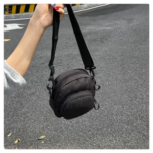 Detail of compact black nylon crossbody bag with dual zipper layers and adjustable strap