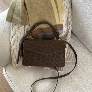 Detail of leopard print handbag texture with golden hardware on a soft sofa