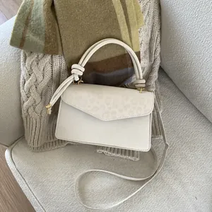 Detail of cream crossbody bag with leopard print flap and elegant gold hardware