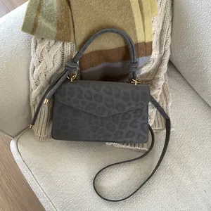 Detailed view of leopard print crossbody bag with gold hardware on soft cozy fabrics