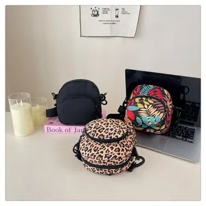 Detailed view of mini nylon crossbody bags in black, leopard print, and tropical leaf patterns