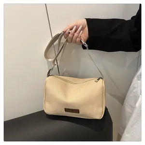 Détail du sac bandoulière en nylon abricot avec sangle réglable et étiquette en cuir