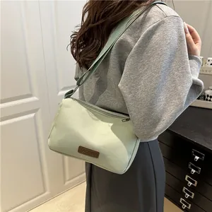 Sac à bandoulière minimaliste en toile vert clair avec large sangle et écusson mode