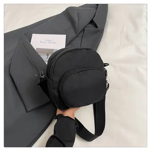 Detailed macro view of black nylon shoulder bag with adjustable strap and dual zippers