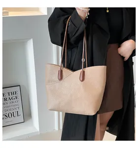 Detail of a beige pebbled leather tote bag with brown straps styled with a trench coat