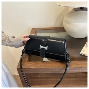 Close-up of black leather underarm bag with silver H-shaped buckle and knotted strap detail