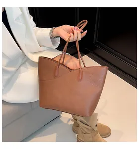 Close-up of brown litchi grain leather tote bag with unique V-shaped stitching and dual handles