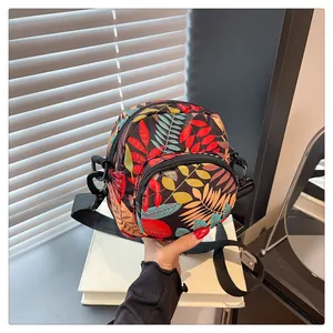 Detail of floral nylon crossbody bag with colorful leaf prints and adjustable strap