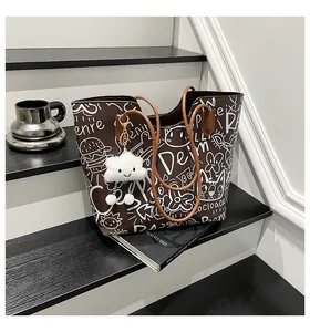 Dettaglio di una borsa tote marrone con graffiti e ciondolo a nuvola su una scala moderna