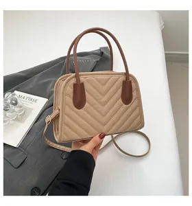 Close-up of V-shaped quilted beige leather bag with dark brown top handle and zipper