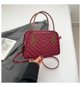 Detail of burgundy quilted PU leather handbag with V-stitch and gold dual zippers