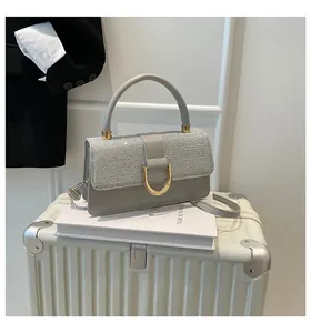 Detail of grey leather handbag with silver glitter flap and gold D-shaped buckle lock