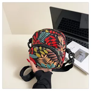 Detail of colorful leaf pattern crossbody bag with dual zippers and adjustable strap