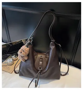 Detail view of a dark brown matte leather tote bag featuring a silver floral buckle and tassel