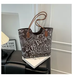 Dettaglio di una borsa tote in pelle marrone con stampe graffiti bianche e manici lunghi