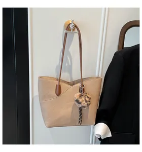 Close-up of beige pebble leather tote with brown straps and leopard plush charm