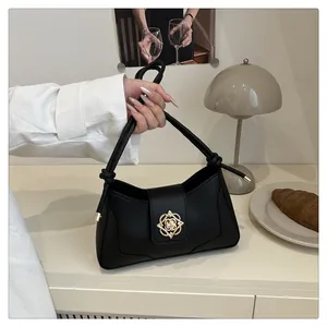 Détail d'un sac à main noir en cuir avec fermoir floral doré et bandoulière nouée