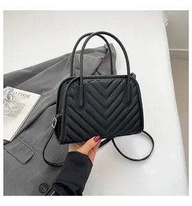 Detailed view of black V-quilted handbag with double handles and metallic hardware