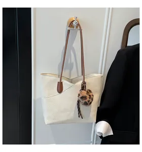 Detail of off-white tote bag with lychee texture, V-shaped cut and leopard pompom