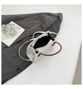 Detail of white quilted leather handbag with contrasting brown round top handles