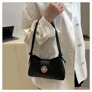 Détail du sac sous le bras noir avec fermoir fleuri doré et bandoulière à nœuds
