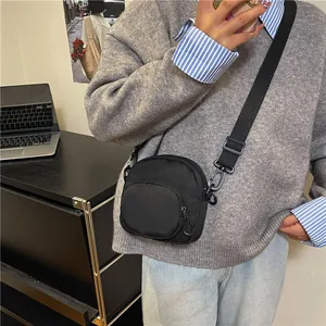 Minimalist black nylon crossbody bag for women with adjustable strap in casual interior setting