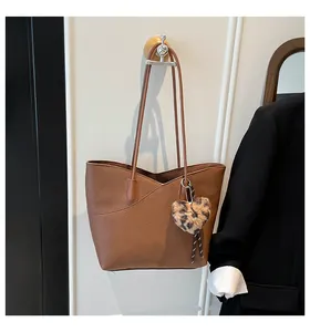 Detailed texture of brown pebble leather tote bag with leopard heart charm pendant