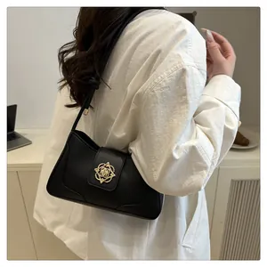 Détail d'un sac à main en cuir noir avec boucle fleurie dorée et bandoulière nouée
