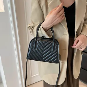 Classic black quilted handbag with V-shaped texture and strap shown on model