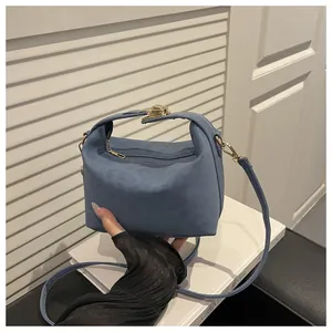 Detailansicht der dunkelblauen Wildledertasche mit Metallverschluss auf weißen Büchern