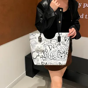 Borsa tote bianca con graffiti neri e ciondolo a nuvola indossata da una modella