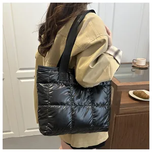 Macro shot of black quilted nylon tote bag with glossy finish and wide woven straps