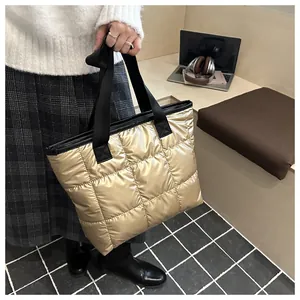 Close-up of golden quilted puffer tote bag with black strap showing padded texture