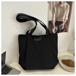 Détail du sac cabas en nylon noir avec écusson en cuir FASHION et bandoulière large