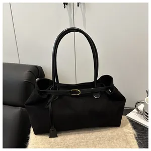 Detail of black suede shoulder bag with golden buckle and sleek leather handles