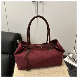 Detail of burgundy suede tote bag featuring golden square buckle and long shoulder strap